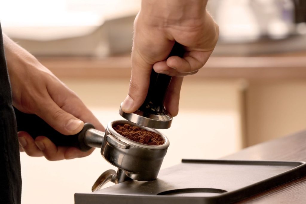 barista temping coffee with portafilter