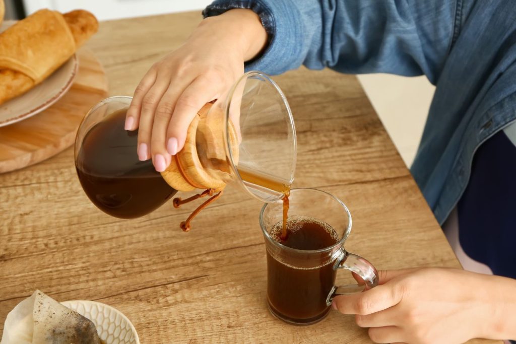 Pouring coffee from cheme coffee maker after brewing